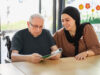 Pflegerin liest mit Senior