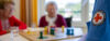 Logo Schwesternschaft im Vordergrund Spiel mit Seniorinnen im Hintergrund